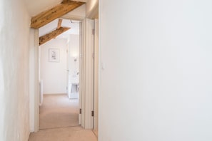 A narrow hallway with a wooden beam ceiling, leading to a bathroom with a toilet and a shower. - Carew Cottage, Holiday Cottage Carew, Sleeps 4, 2 bedrooms,  bathrooms (Tenby)