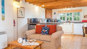 Una sala acogedora con un sofá, una mesa de centro y una cocina al fondo.