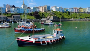Un puerto con barcos amarrados, una aguja de iglesia y edificios coloridos a lo largo del muelle.