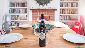 A dining table with a bottle of wine, glasses, and plates in a room with bookshelves and a mirror on the wall. - Cherry Tree House, Holiday Cottage St Davids, Sleeps 5, 3 bedrooms,  bathrooms (Haverfordwest)