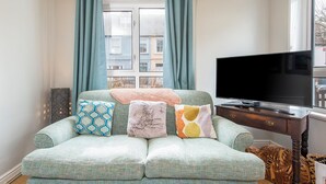 A living room with a sofa, a television, and a window with curtains. - Cherry Tree House, Holiday Cottage St Davids, Sleeps 5, 3 bedrooms,  bathrooms (Haverfordwest)
