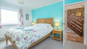 Quarto com cama, mesas de cabeceira, janela com cortinas, cabeceira de madeira e escada.
