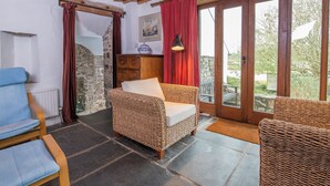 Una habitación acogedora con muebles de mimbre, una pared de piedra y vistas a través de un ventanal.