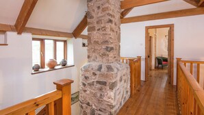 Un interior de madera con un pilar de piedra, vigas de madera y una barandilla de madera.