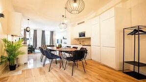 A modern kitchen with wooden flooring, a dining area with a round table and chairs, and a hanging light fixture.
