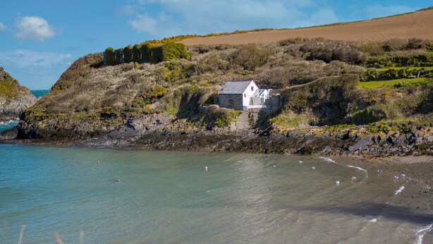 A coastal scene with a stone house on a cliff, overlooking a beach with clear water and a calm sea. - Doves Cottage, Holiday Cottage Abercastle, Sleeps 2, 1 bedrooms,  bathrooms (Haverfordwest)