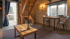 A rustic room with a wooden table, a staircase, and a window with a view. - Doves Cottage, Holiday Cottage Abercastle, Sleeps 2, 1 bedrooms,  bathrooms (Haverfordwest)