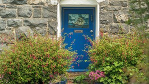A stone building with a blue door and a small window above it.
