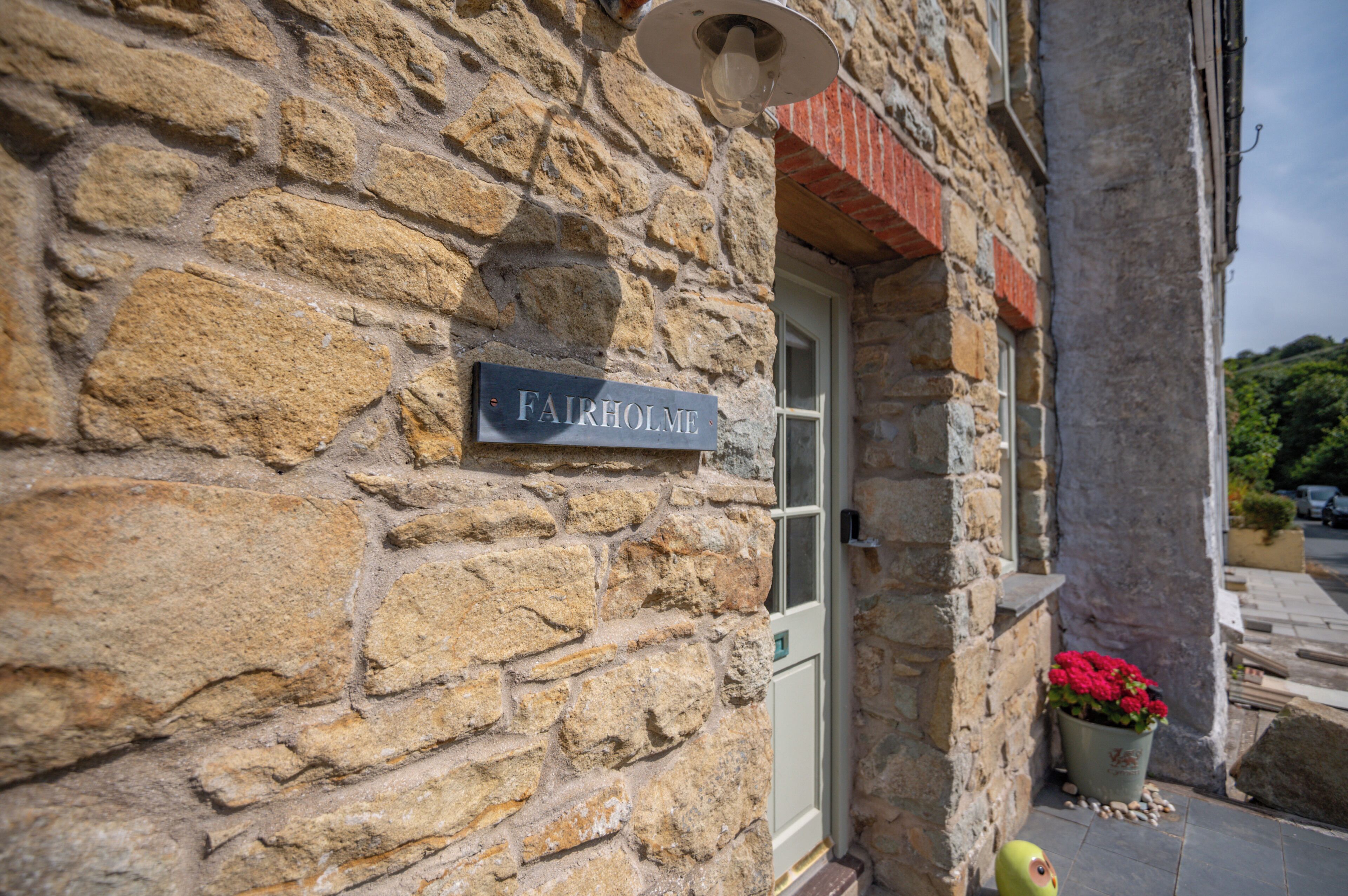 A stone building with a sign reading 'FAIRHOLME' and a door.