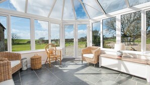 A conservatory with wicker furniture, large windows, and a view of the countryside. - Felin Fach, Holiday property Llandeloy, Sleeps 8, 4 bedrooms,  bathrooms (Haverfordwest)