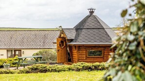 A wooden cabin with a sloped roof and a chimney, surrounded by a well-maintained lawn and a picnic table. - Gamekeepers Cottage, Holiday Cottage Nr St Brides, Sleeps 6, 3 bedrooms,  bathrooms (Haverfordwest)