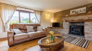A living room with a leather sofa, a glass coffee table, a stone fireplace, and a television. - Gamekeepers Cottage, Holiday Cottage Nr St Brides, Sleeps 6, 3 bedrooms,  bathrooms (Haverfordwest)