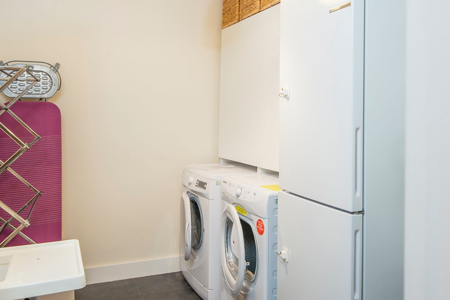 Une buanderie équipée d’un lave-linge, d’un sèche-linge et d’un étendoir.