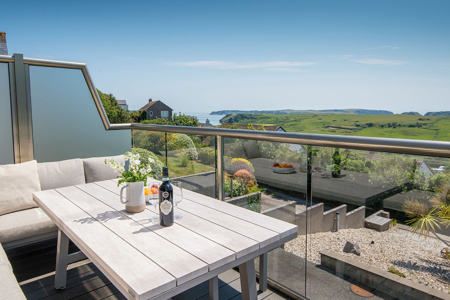 A balcony with a table, seating, and a view of the countryside.
