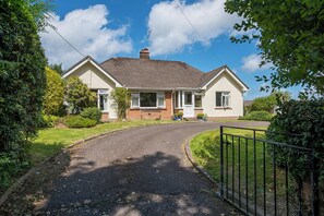 A two-story house with a paved driveway leading to the front door, surrounded by greenery and a clear sky. - Glandraeth, Holiday Cottage Newport, Sleeps 4, 2 bedrooms,  bathrooms (Newport)
