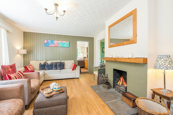 A living room with a sofa, ottoman, fireplace, and a wall with a colorful artwork. - Glandraeth, Holiday Cottage Newport, Sleeps 4, 2 bedrooms,  bathrooms (Newport)