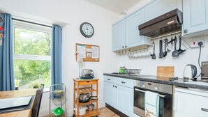 A modern kitchen with light blue cabinets, a stainless steel oven, and a wooden cart with kitchenware. - Glen Holme, Holiday Apartment Little Haven, Sleeps 3, 1 bedrooms,  bathrooms (Little Haven)