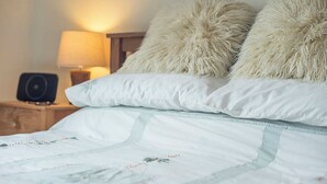 A neatly made bed with white and light blue bedding, two fluffy pillows, a bedside lamp, and a speaker on a wooden nightstand. - Glen Holme, Holiday Apartment Little Haven, Sleeps 3, 1 bedrooms,  bathrooms (Little Haven)