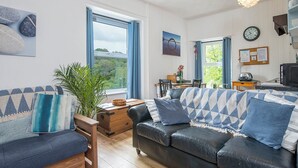 A cozy living room with a leather sofa, a wooden chest, and a dining area with a table and chairs. - Glen Holme, Holiday Apartment Little Haven, Sleeps 3, 1 bedrooms,  bathrooms (Little Haven)