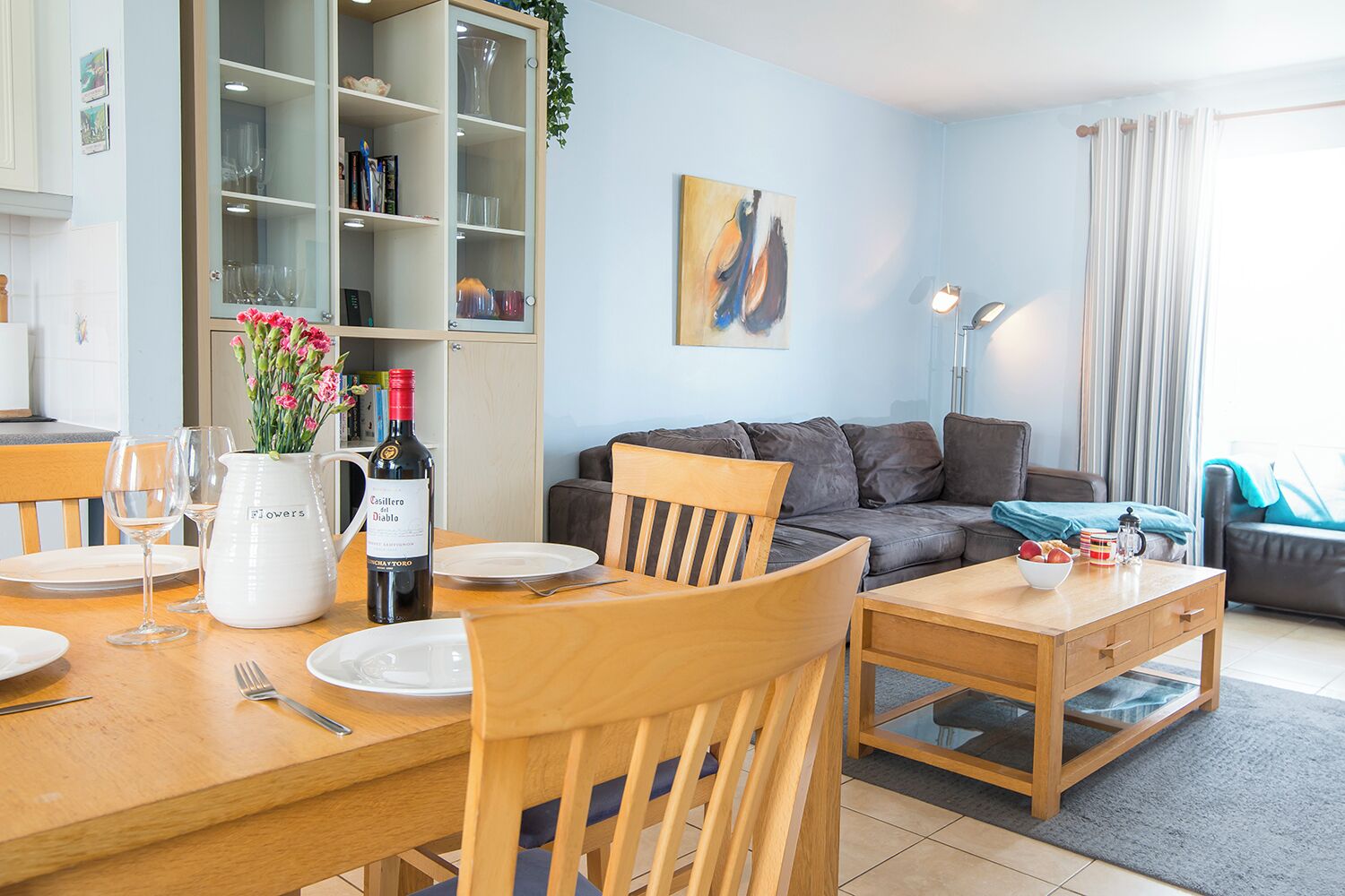 A modern living room with a dining area, a sofa, and a bookshelf.