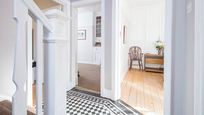 A hallway with a checkered floor leading to a room with a wooden floor, white walls, and a door with a picture frame. - Gorwel, Holiday Home St Davids, Sleeps 6, 3 bedrooms,  bathrooms (Haverfordwest)