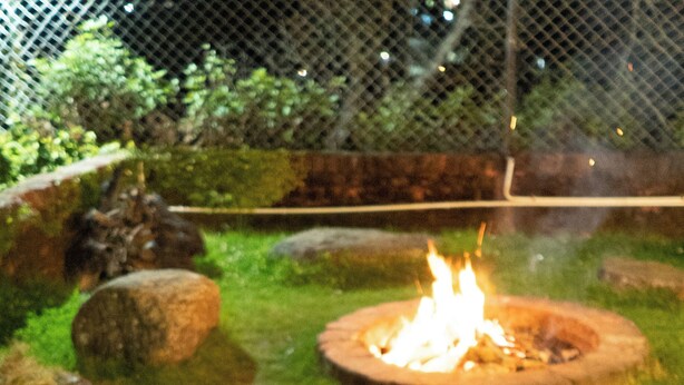 A table set outdoors with plates, cutlery, and a pot, surrounded by rocks and a fire pit. - Kodaikanal Misty Family Resort (Kodaikanal)