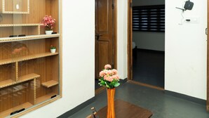 A room with a wooden shelf unit, a wooden door, and a wall-mounted device. - Kodaikanal Misty Family Resort (Kodaikanal)