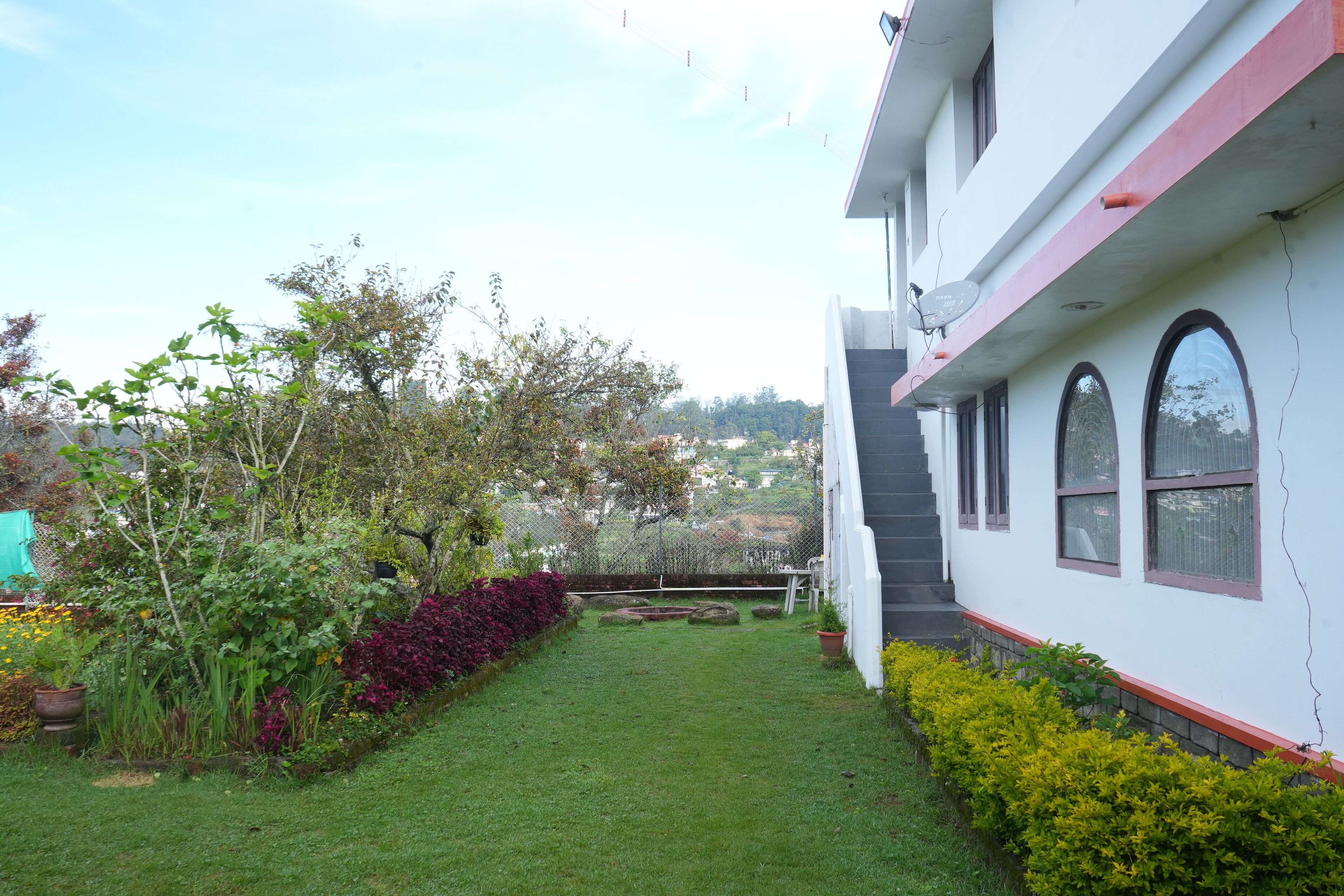 A modern building with a white exterior and red accents, a well-maintained garden with various plants, and a clear view of the surrounding area.