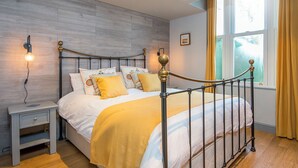 A neatly arranged bedroom with a bed, bedside tables, and a window with curtains.