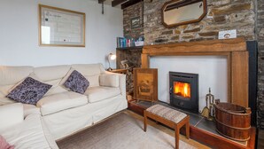 A cozy living room with a stone wall, a fireplace, a sofa, and a small table. - Green Plains, holiday home Wisemans Bridge, Sleeps 6, 3 bedrooms,  bathrooms (Narberth)