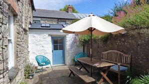 A stone building with a blue door, a wooden bench, a table, and a turquoise chair. - Greystones House, Holiday Home St Davids, Sleeps 6, 3 bedrooms,  bathrooms (Haverfordwest)
