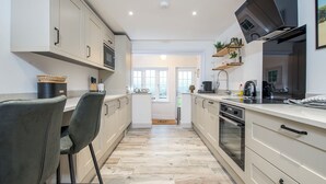 Une cuisine moderne avec des meubles de couleur claire, un îlot central et une vue sur l’extérieur.