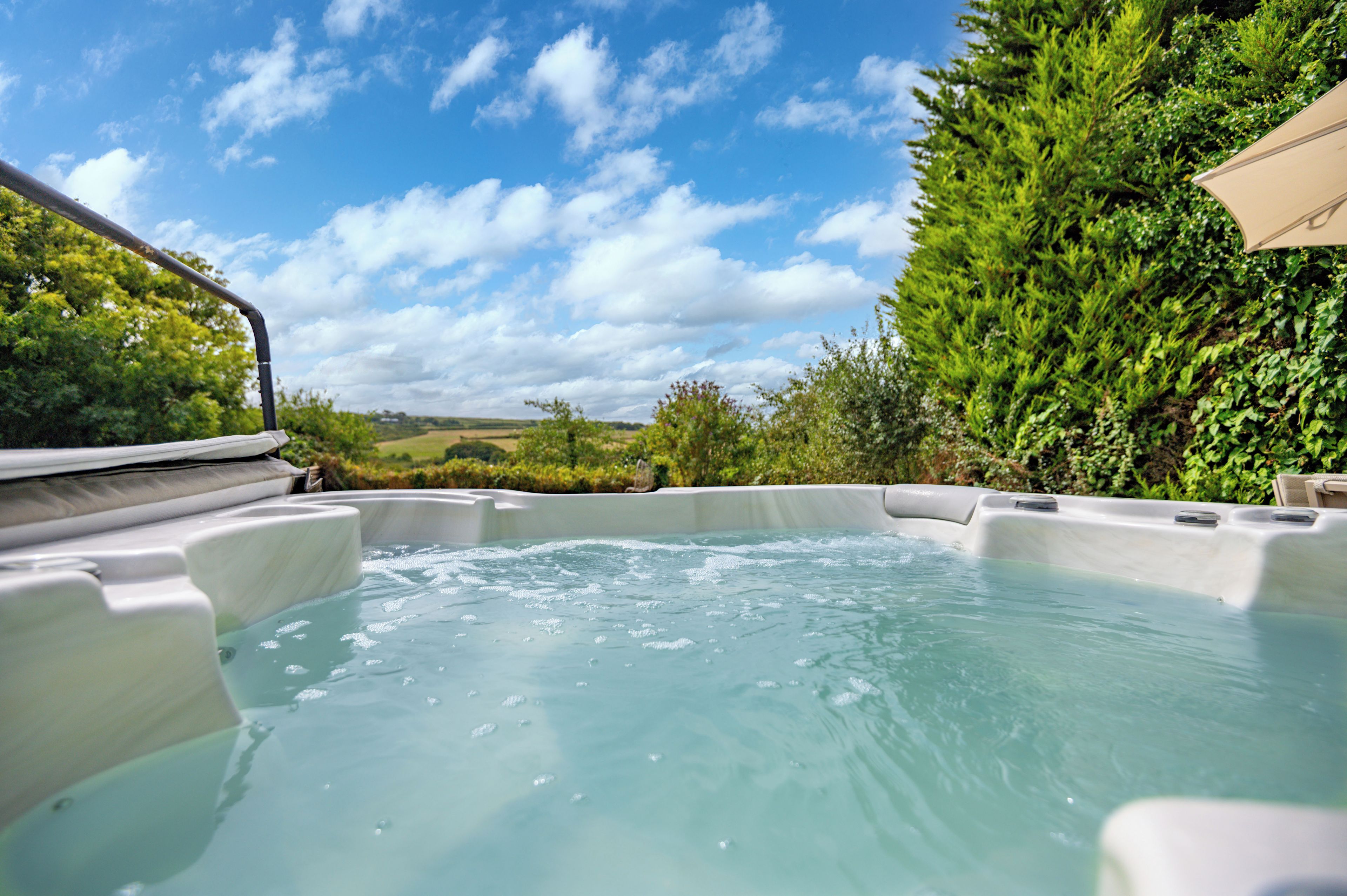 A hot tub with a view of a green landscape and a clear sky.