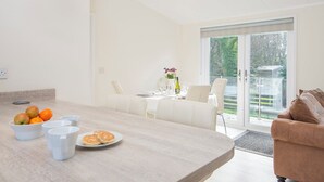 Eine moderne Küche mit einer großen Kochinsel, Essbereich mit weißer Möbel und eine Schiebeglastür, die auf eine Terrasse führt.