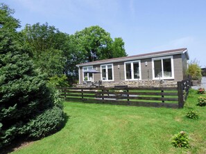 A two-story house with a stone foundation, large windows, and a fenced backyard.
