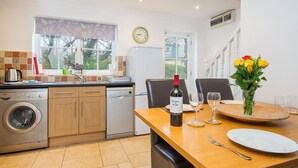 A modern kitchen with a dishwasher, washing machine, and a dining area with a table set for two. - Hazelbrook Cottage, Holiday Cottage Amroth, Sleeps 4, 2 bedrooms,  bathrooms (Amroth)