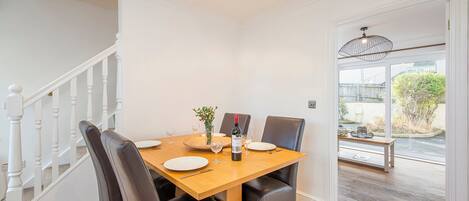 A dining area with a wooden table, black chairs, and a bottle of wine.