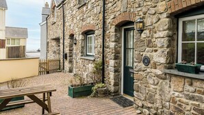 A stone building with a wooden bench, a door with a number plate, and a window with a plant on the windowsill. - Hazelbrook Cottage, Holiday Cottage Amroth, Sleeps 4, 2 bedrooms,  bathrooms (Amroth)