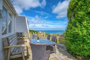 A patio with a table and chairs, a wooden fence, and a view of the ocean. - Heddfan Cottage, Holiday Home Little Haven, Sleeps 4, 2 bedrooms,  bathrooms (Haverfordwest)