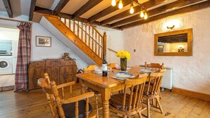 A dining area with a wooden table and chairs, a staircase, and a mirror on the wall. - Honey Hook Cottage, Holiday Cottage Nolton, Sleeps 5, 2 bedrooms,  bathrooms (Haverfordwest)