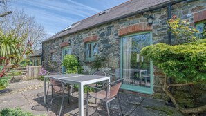 A stone building with a patio table and chairs, a window with a curtain, and a small garden area. - Honeysuckle Cottage, Holiday Cottage Lochvane, Nr Solva, Sleeps 5, 2 bedrooms,  bathrooms (Solva)