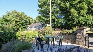 An outdoor patio with a table and chairs, surrounded by lavender plants and a stone wall. - Inglenook House, Holiday Home Manorbier, Sleeps 8, 4 bedrooms,  bathrooms (TENBY)
