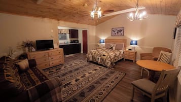 A cozy room with a bed, a sofa, a dining table, and a TV.