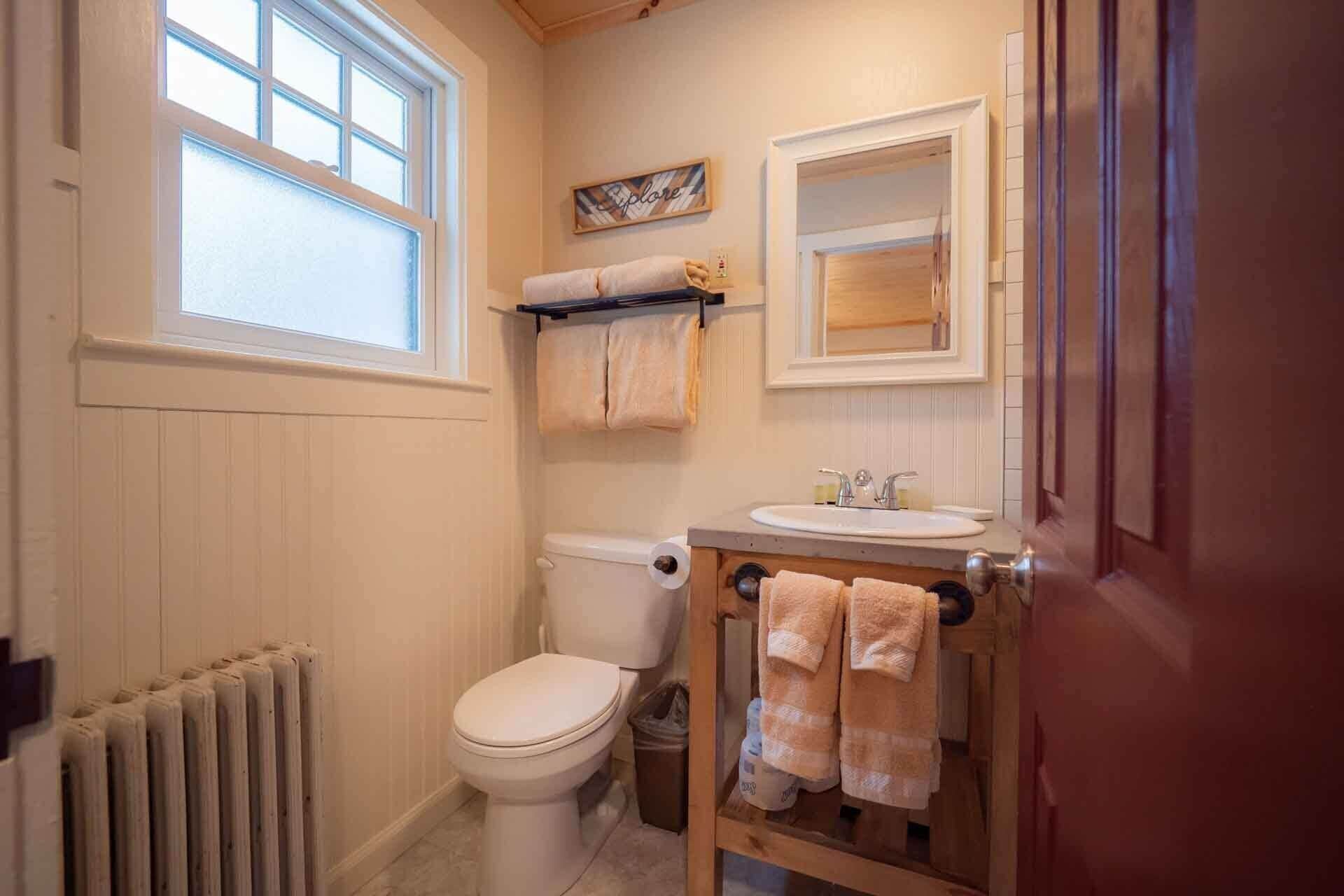 Un baño pequeño con inodoro, lavamanos y ventana.
