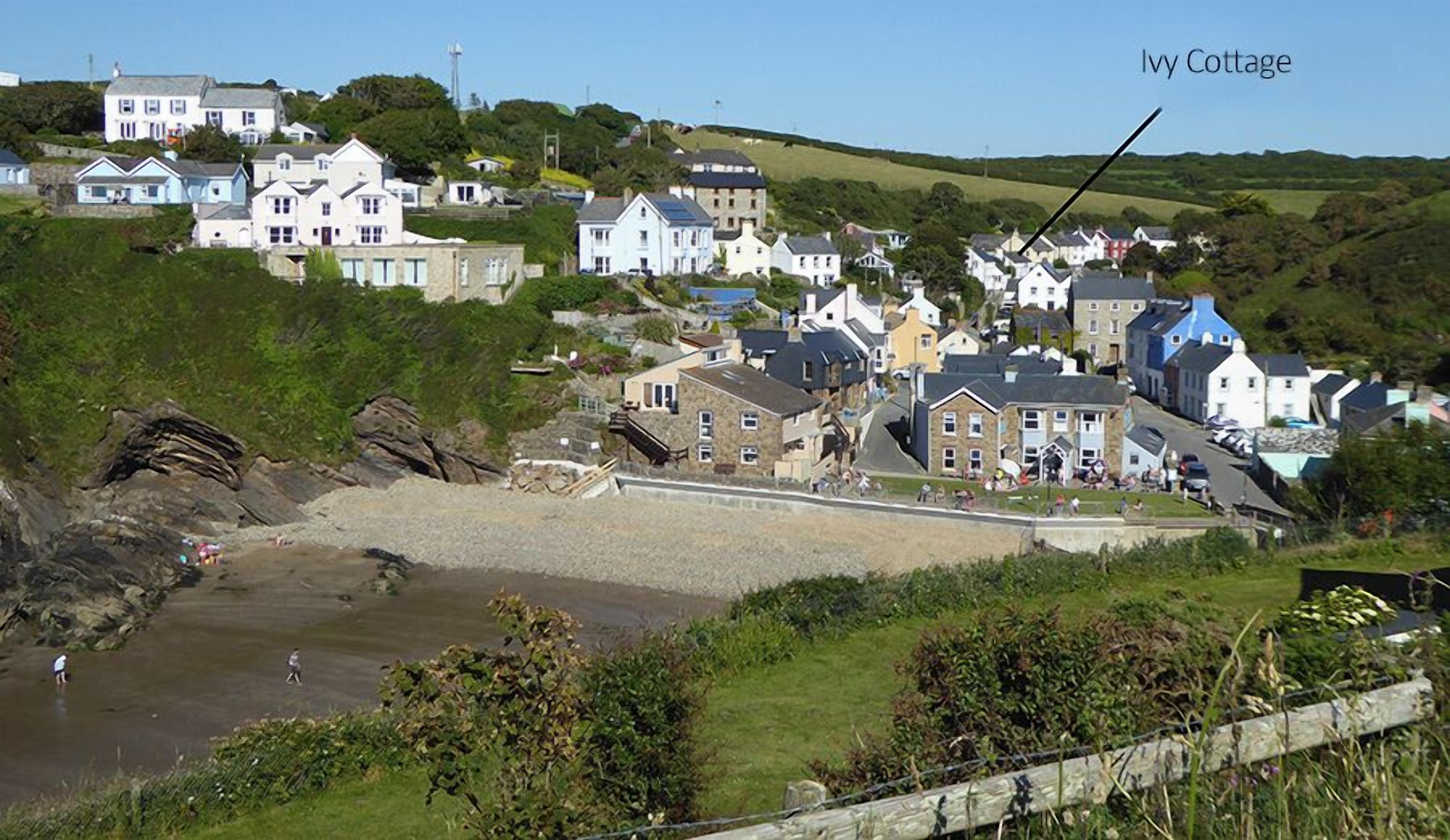 Un village côtier avec des maisons, une plage et une maison particulière reconnaissable à sa façade couverte de lierre.