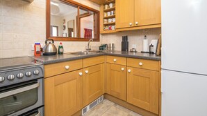A kitchen with wooden cabinets, a stainless steel stove, and a white refrigerator. - Ivy Cottage, Holiday Cottage Little Haven, Sleeps 5, 2 bedrooms,  bathrooms (Haverfordwest)