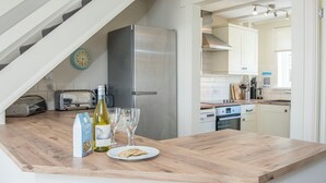 A kitchen with a wooden countertop, stainless steel appliances, and a clock on the wall. - Ivy Tower House, Holiday Home Ivy Tower Village, St Florence, Sleeps 12, 6 bedrooms,  bathrooms (Tenby)
