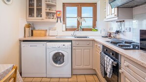 A compact kitchen with a washing machine, a built-in oven, and a window with a view. - Kingfisher Cottage, Holiday Cottage St Ishmaels, Near Dale, Sleeps 4, 2 bedrooms,  bathrooms (Haverfordwest)