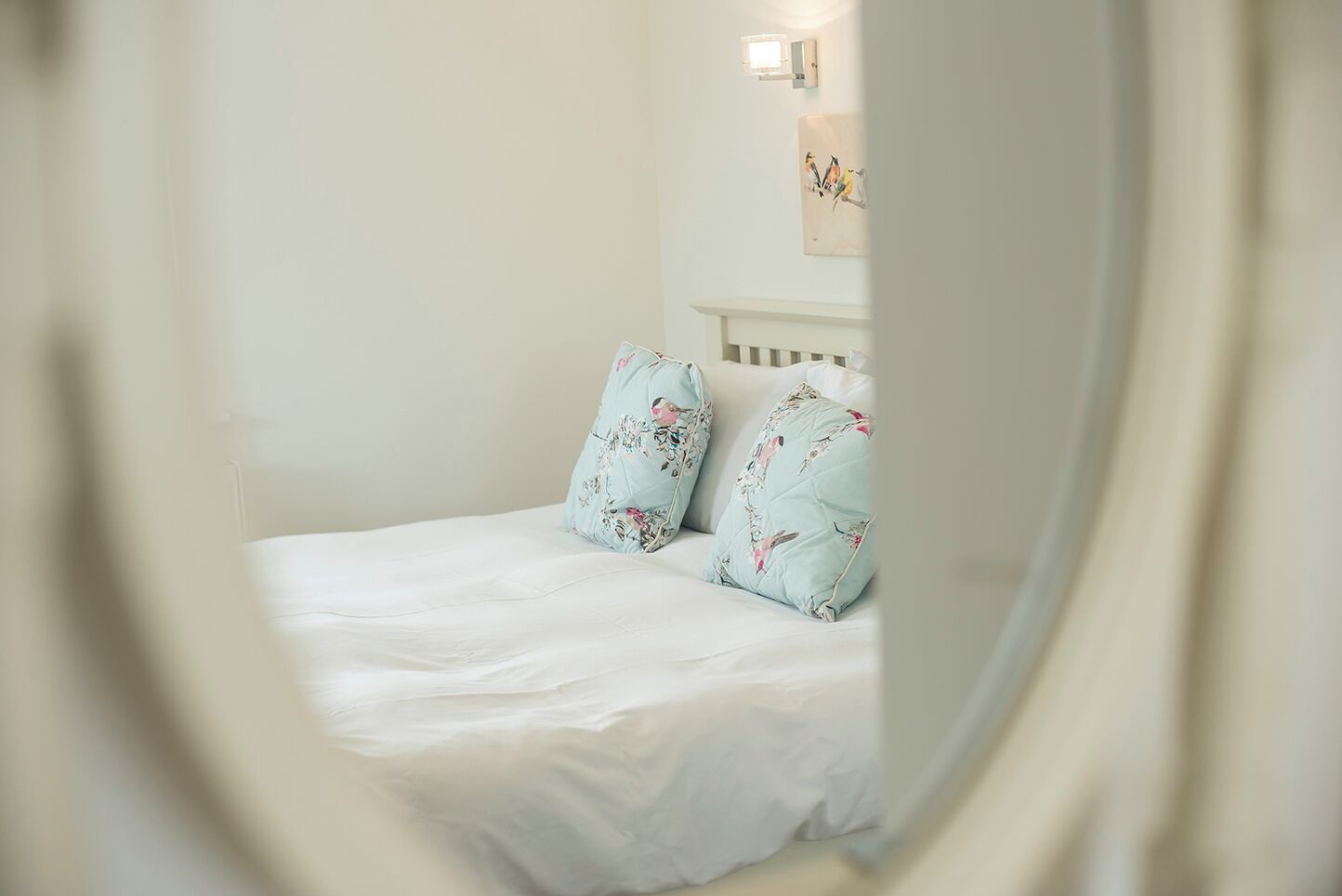 Un lit avec des coussins à motifs floraux et une tête de lit blanche.