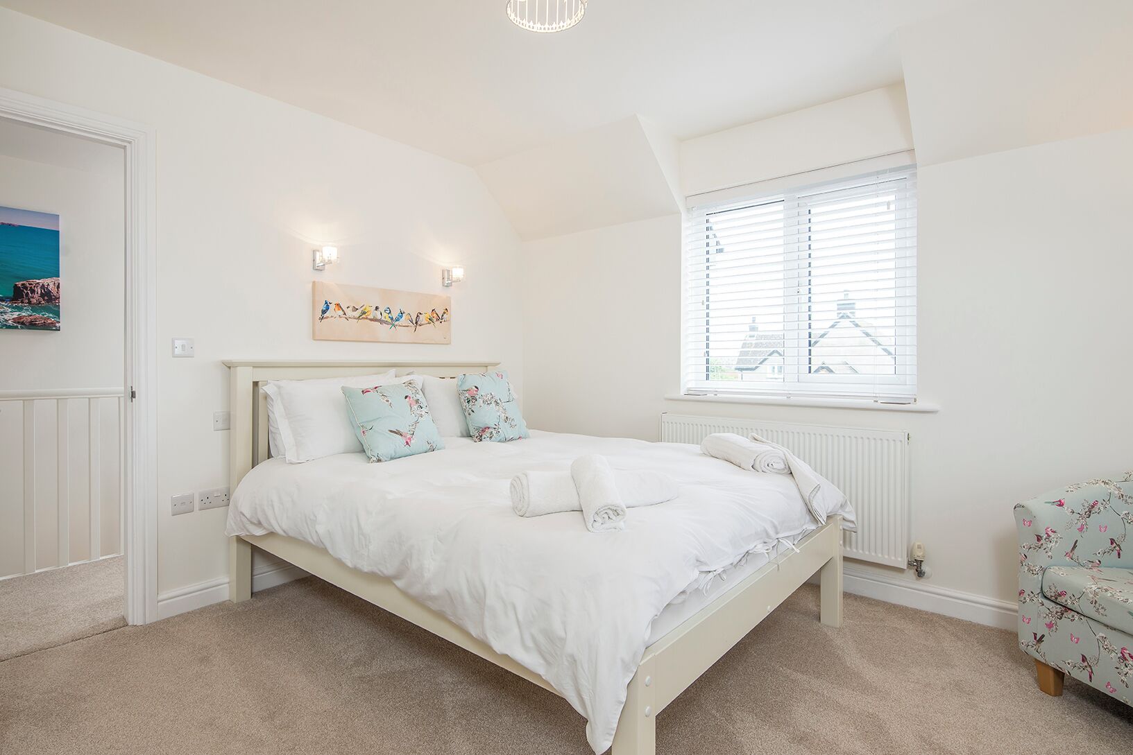 A bedroom with a bed, a window with blinds, a radiator, and a wall-mounted picture.